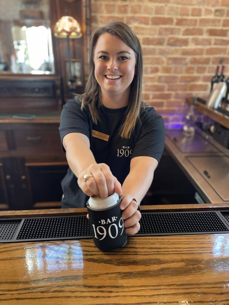 Smiling Bartender opens a cold beer for a guest