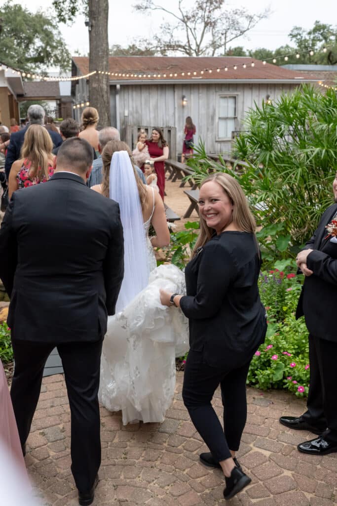 Wedding coordinator carrying bride's dress at Butler's Courtyard, an all-inclusive venue near Houston Texas.