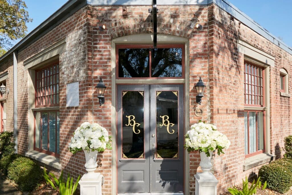 Front doors of Butler's Courtyard a historic Houston Texas wedding venue with white wedding florals on each side of the door