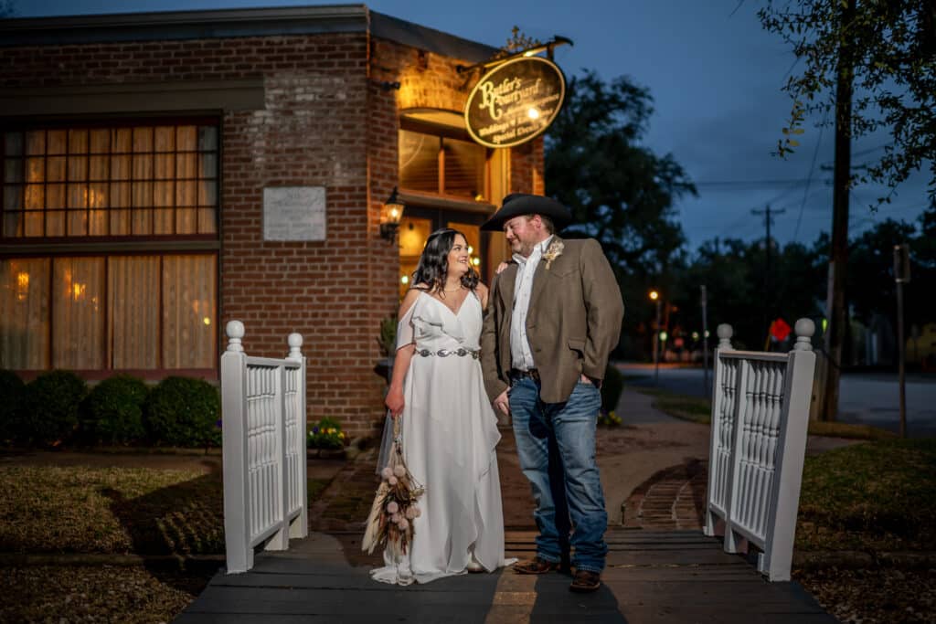 Cowboy Groom and his Bride in front of Butler's Courtyard a premiere Houston wedding venue full of Texas History