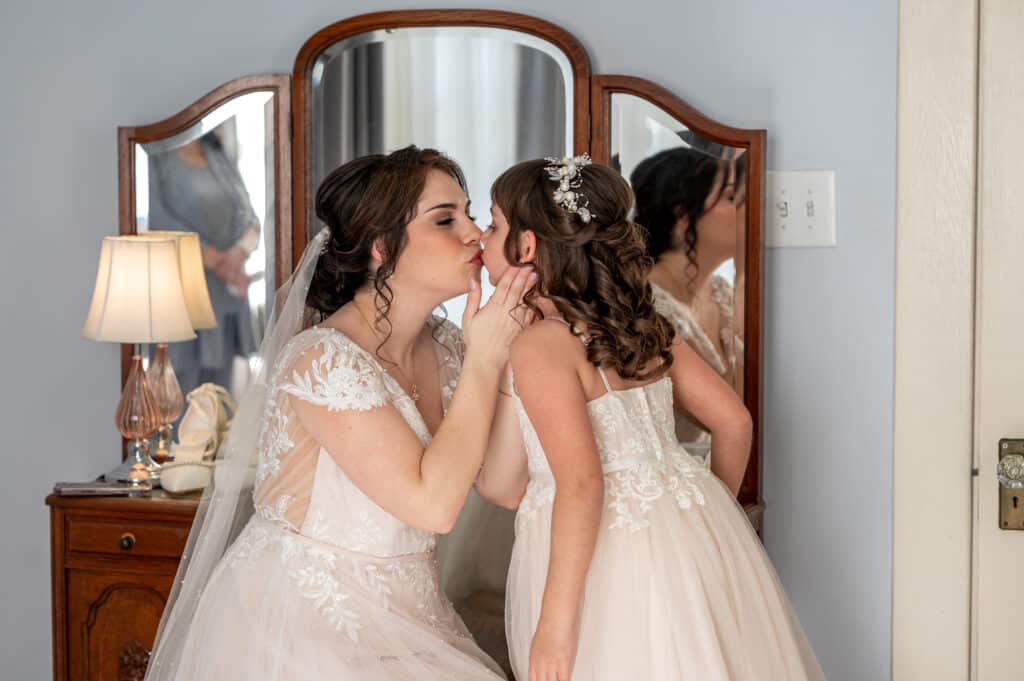 Bride and groom join their daughter in a heartfelt sand unity ceremony during their wedding at Butler's Courtyard, symbolizing family unity and love in a beautiful and memorable celebration.