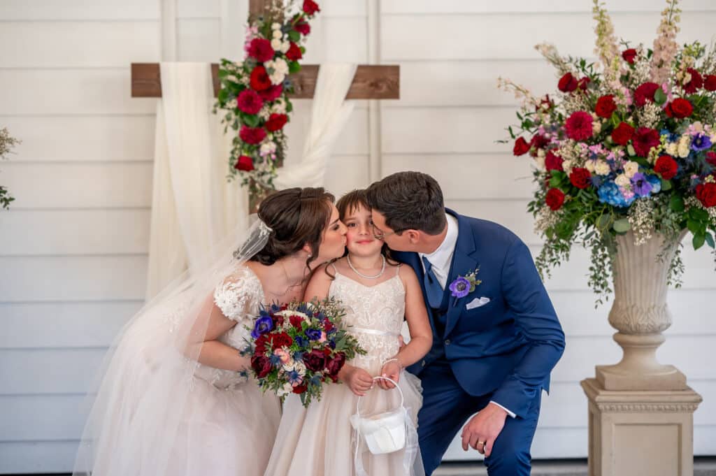 Bride and Groom kiss their daughter, also the flower girl. 