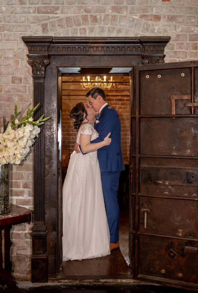 Bride and Groom share a kiss in the doorway of the antique bank vault one of many unique features at Butler's Courtyard in League City