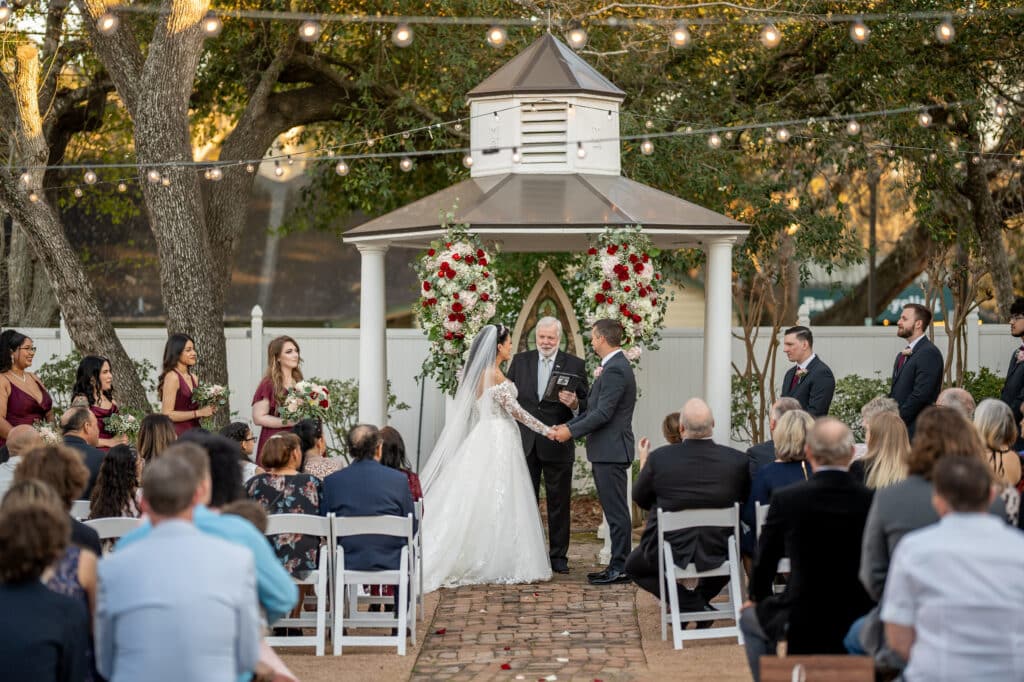 Bride and Groom get married in front of the wedding gazebo at Butler's Courtyard surrounded by Lush florals