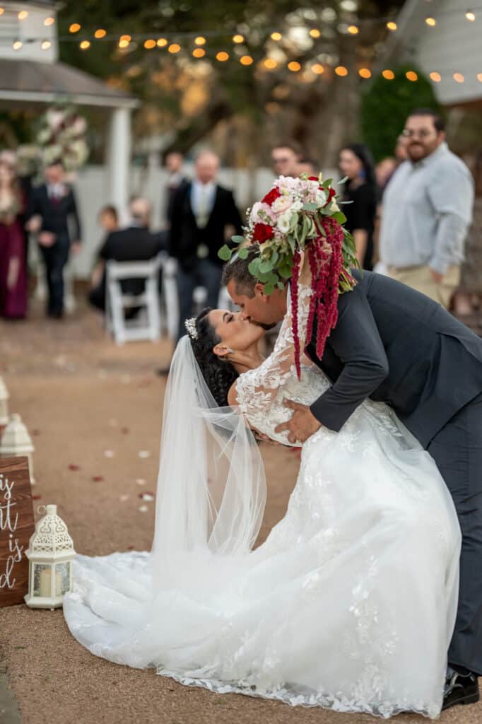 Groom dips and kisses a Bride at the end of their wedding aisle