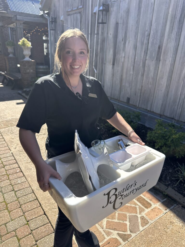 Hardworking Team member smiles as she is bussing tables at a wedding