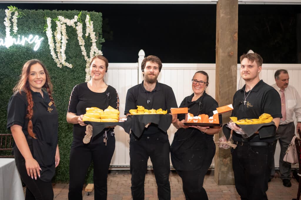 Full Service Wedding Venue team smiles as they serve wedding late night bites to wedding guests in Houston