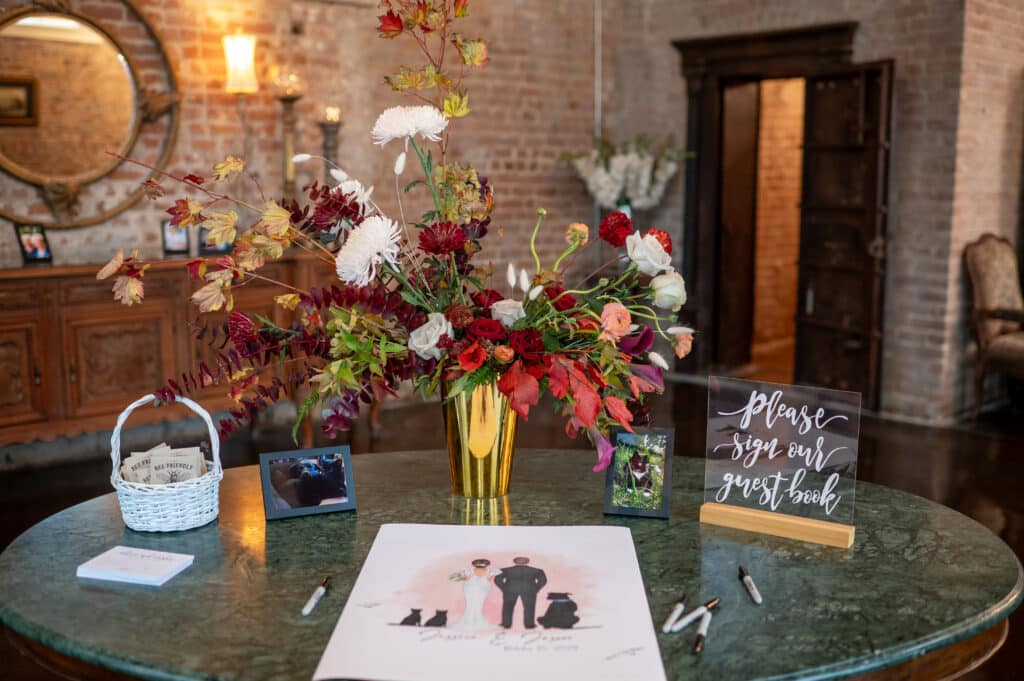Wedding welcome table elegantly decorated with vibrant fall colors, featuring seasonal floral arrangements, rustic accents, and charming autumn-inspired details, perfect for a fall wedding in Houston at Butler's Courtyard.