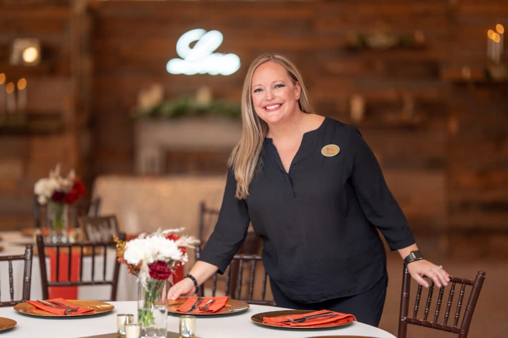 Wedding Coordinator smiles as she makes sure all the details are perfect at a place setting