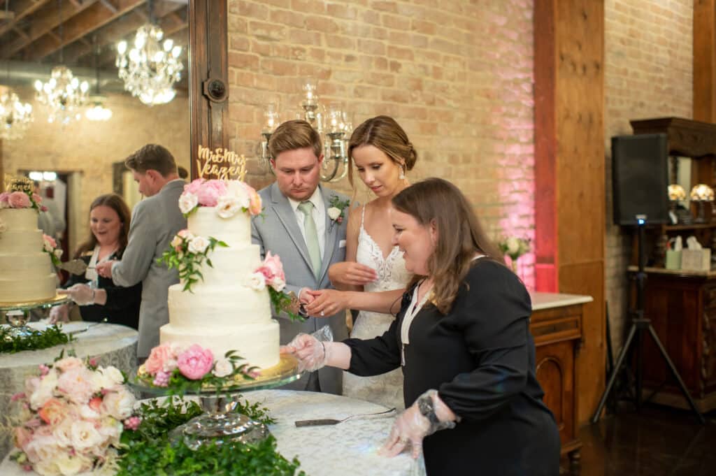 Wedding Coordinator gives instruction to a Bride and Groom on how to cut their perfect wedding cake in Houston