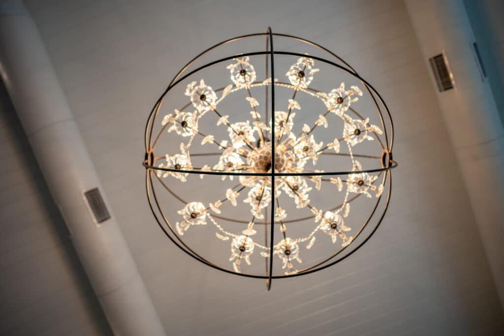Elegant sparkling chandeliers illuminating a wedding ballroom, modern reception space, with natural light and scenic views.