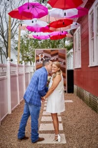 A joyful couple sharing a kiss under umbrellas in the charming Umbrella Alley at Butler's Courtyard, celebrating their elopement.